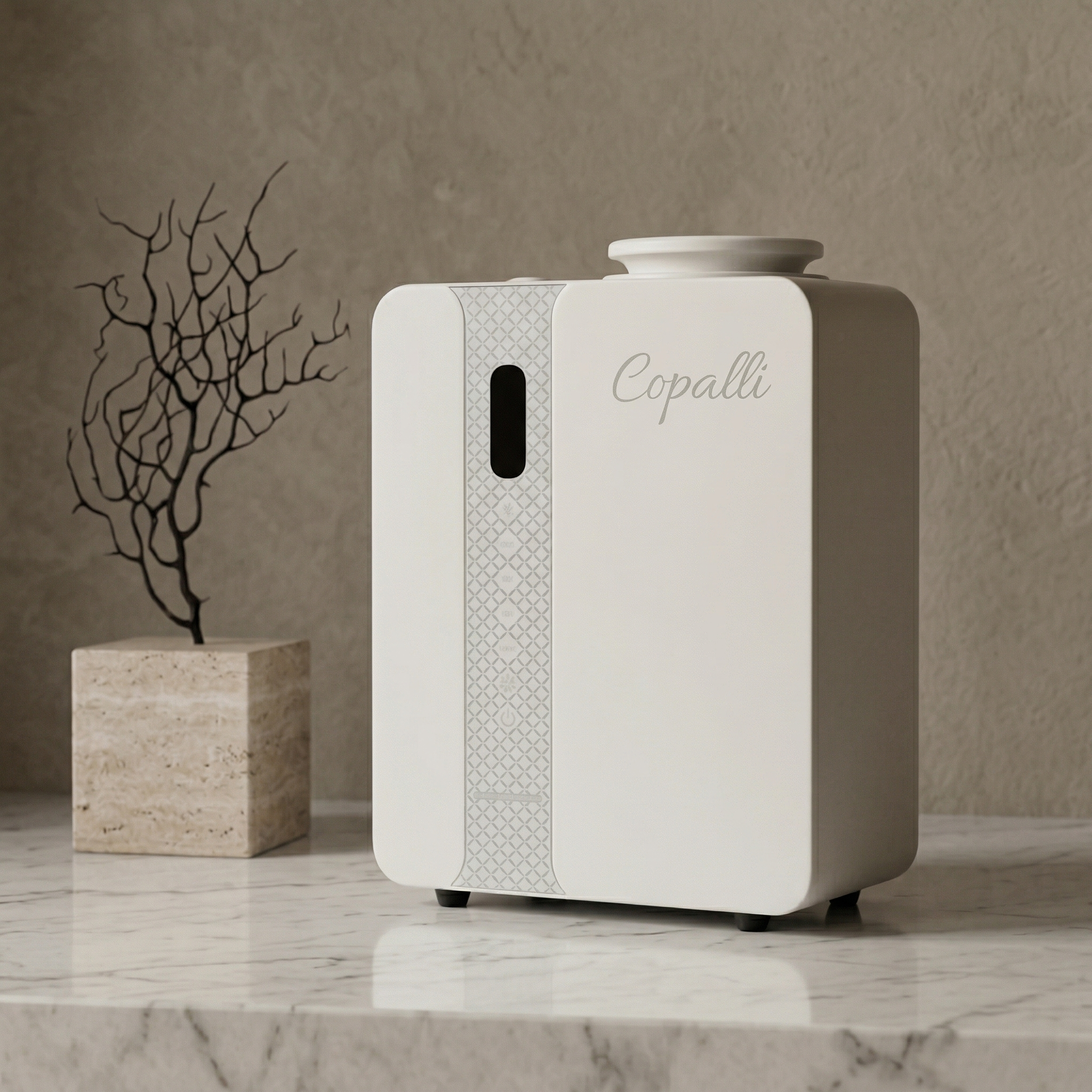 Our white Copalli Pro Diffuser placed on a marble surface next to a decorative dried branch, showcasing its sleek industrial design and minimalist branding against a warm, neutral wall.