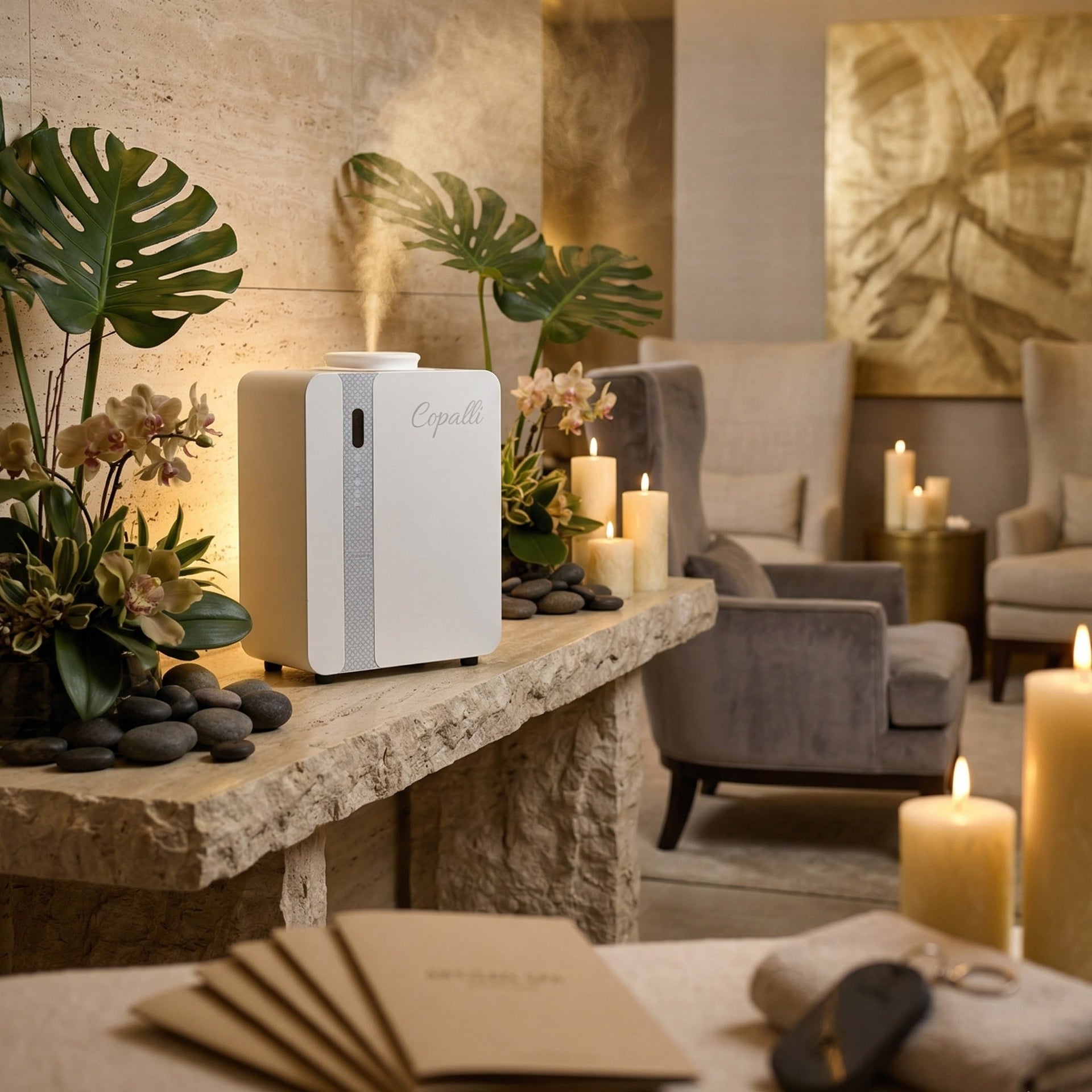 Our white Copalli Pro Plus Diffuser elegantly placed on a stone console in a luxury spa or hotel lobby, surrounded by tropical greenery and candles to create a serene atmosphere.