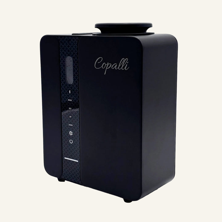 Our black Copalli Pro Diffuser featuring a sleek, rectangular industrial design with a textured side panel and the 'Copalli' logo, centered on a minimalist light cream background.